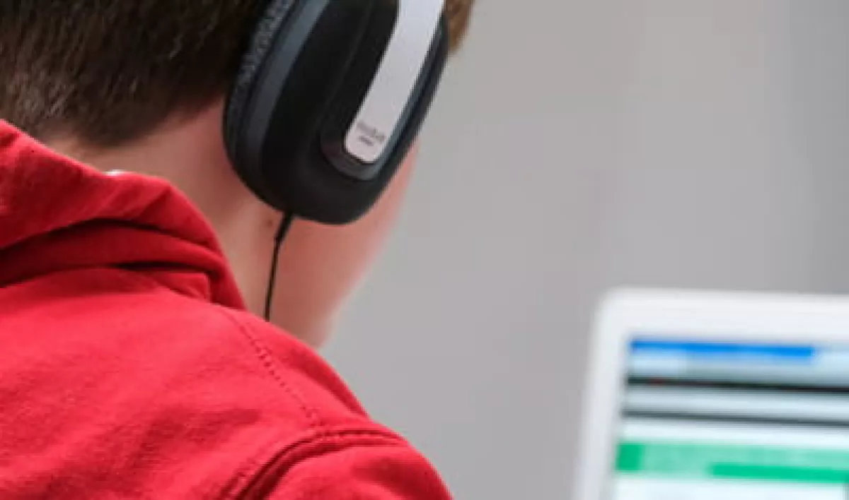 Person wearing headphones and browsing a laptop.